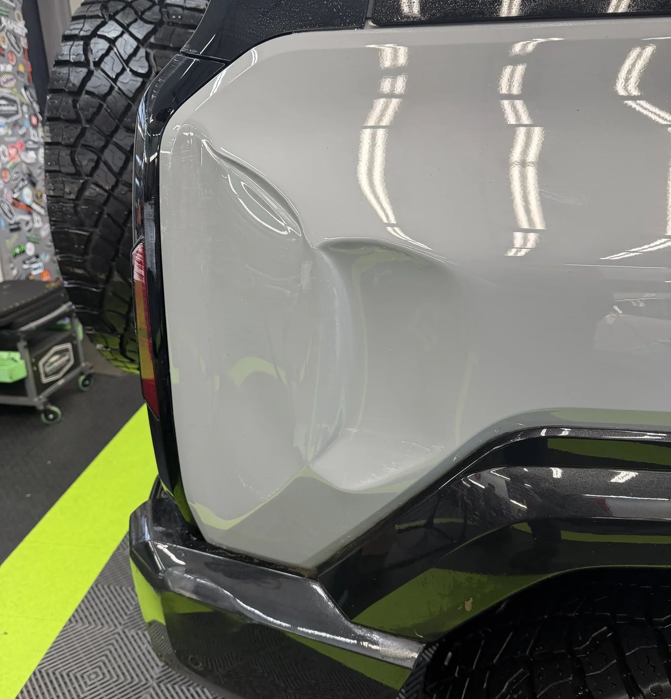 A large dent in the rear quarter panel of a gray off-road SUV before paintless dent repair