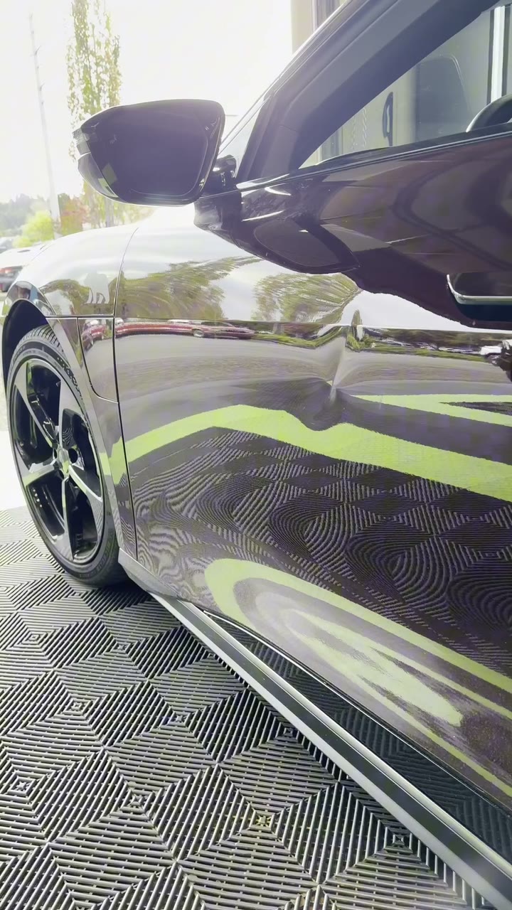 A dark Lucid Air in the Bellevue shop with its door panel being prepared for repair
