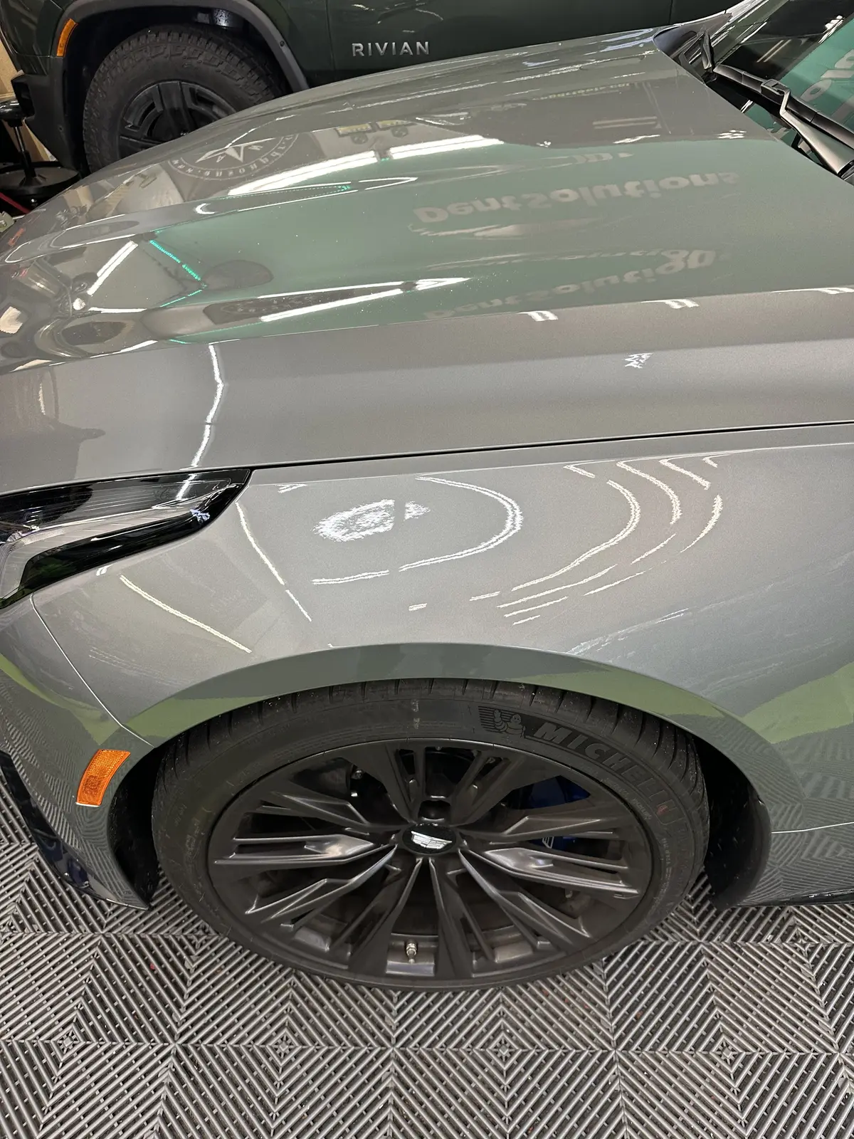 A gray Cadillac front fender after paintless repair, the reflections running straight