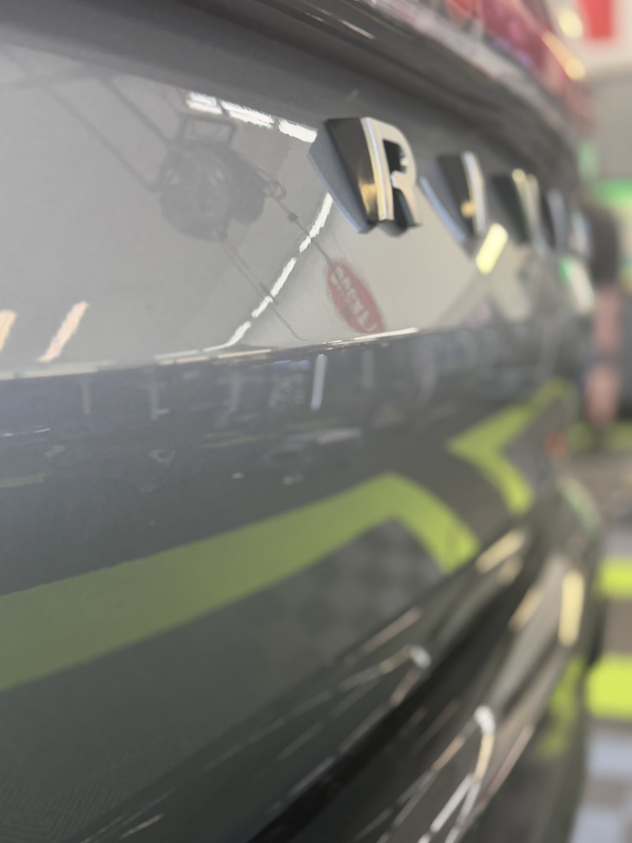 The same Rivian R2 liftgate after paintless dent repair, the reflection running straight and the factory paint untouched