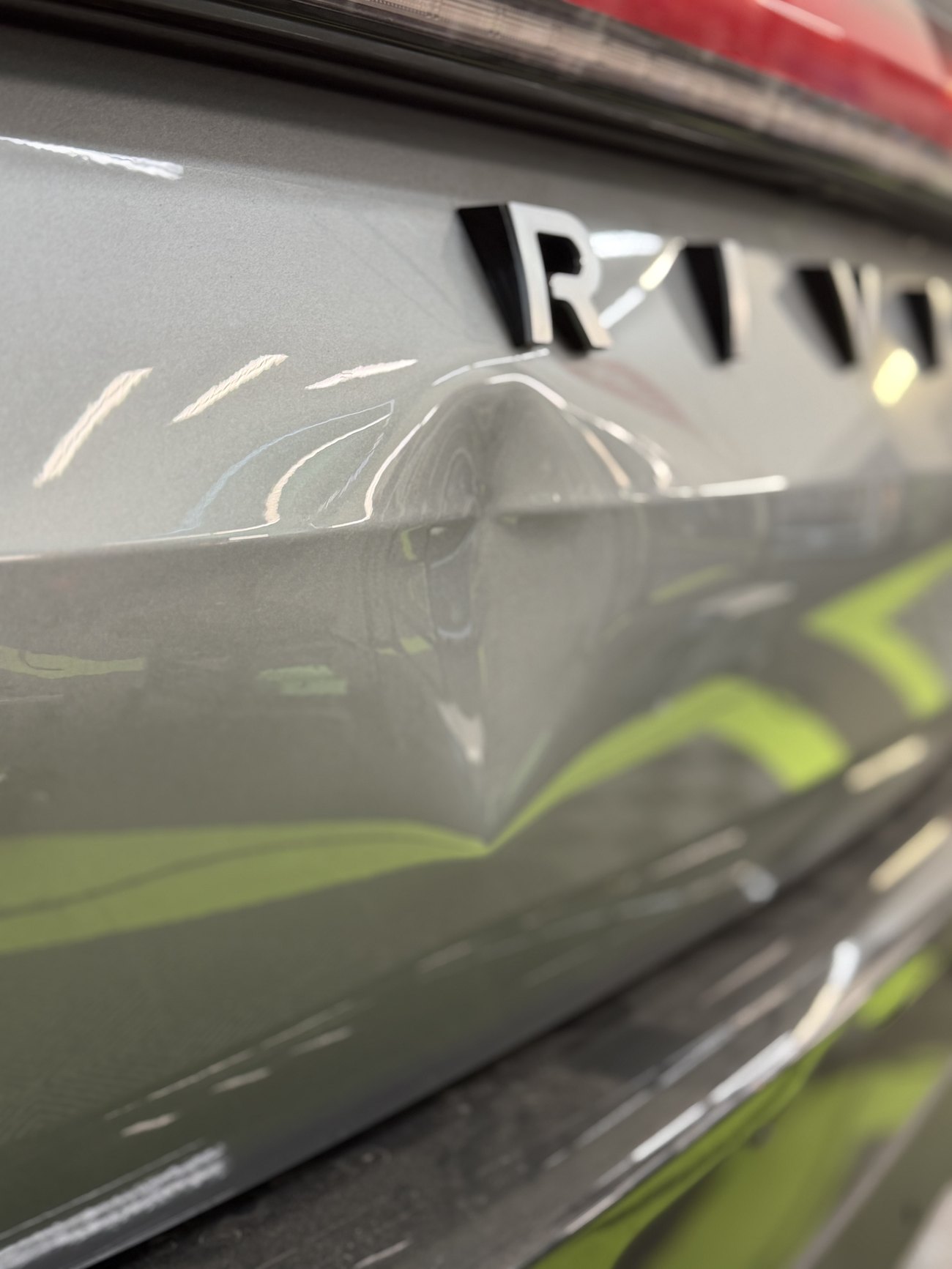 A dent on the rear liftgate of a gray Rivian R2 before paintless dent repair in Bellevue